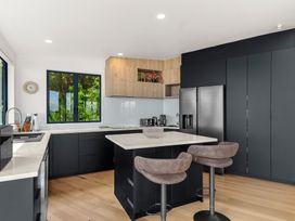 A kitchen with cabinets and bar stools at Langscape - Langs Beach Holiday Home
