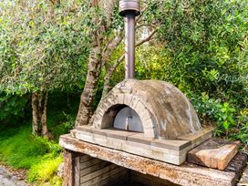 An outdoor pizza oven with chimney in a garden at Langscape - Langs Beach Holiday Home