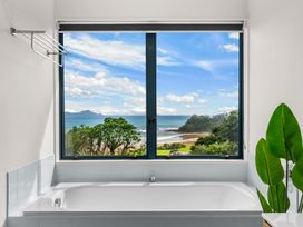 A bathroom with a bathtub and an ocean view at Langscape - Langs Beach Holiday Home