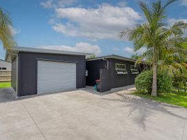 An outdoor area with a garage and palm trees at Tairua Holiday Home in Tairua