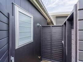 An outdoor shower area with a fence and window at Tairua Holiday Home in Tairua
