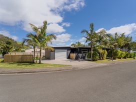 A house with a garage and palm trees at Tairua Holiday Home in Tairua