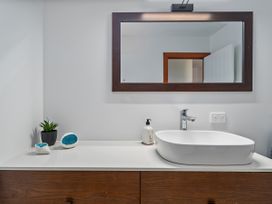 A sink with a mirror and potted plant in a bathroom at Tairua Holiday Home Tairua