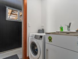 A laundry room with a washing machine and sink at Tairua Holiday Home in Tairua