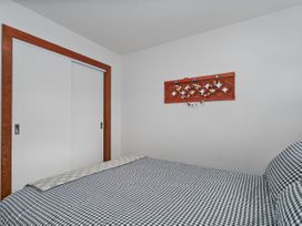 A bedroom with a bed and sliding doors at Tairua Holiday Home in Tairua