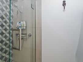 A shower with shelves for toiletries at Tairua Holiday Home in Tairua