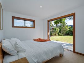 A bedroom with a bed and door leading to garden at Tairua Holiday Home in Tairua