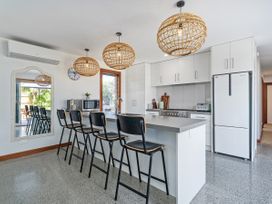 A kitchen with bar stools and appliances at Tairua Holiday Home Tairua