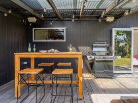 An outdoor dining area with a bar table and stools at Tairua Holiday Home in Tairua