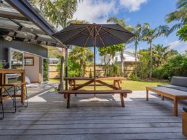 An outdoor area with a table and bench under an umbrella at Tairua Holiday Home in Tairua