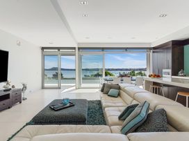 A living room with a view of water and kitchen at Auckland Holiday Home Auckland