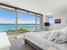 A bedroom with a bed and a view of the sea at Auckland Holiday Home in Auckland
