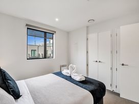 A bedroom with a bed and towels arranged at Christchurch Holiday Apartment in Christchurch