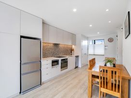 A kitchen with refrigerator, cabinets, and dining table at Christchurch Holiday Apartment in Christchurch