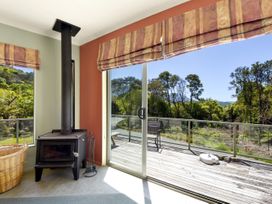 A room with a wood stove and a glass door leading to a deck at Picton in Picton