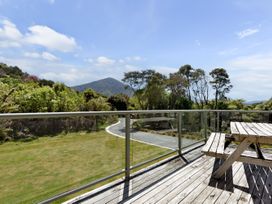 A deck with a table and chairs overlooking a garden and mountains at Picton