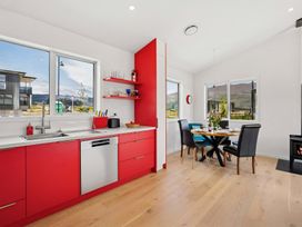 A kitchen with red cabinets and a dining area at Skiwi - Wanaka Holiday Home in Wanaka