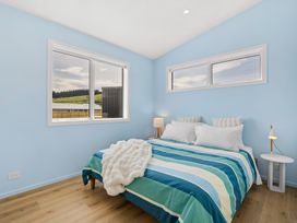 A bedroom with a bed and windows at Skiwi - Wanaka Holiday Home in Wanaka