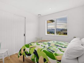 A bedroom with a bed and window showing mountains at Skiwi - Wanaka Holiday Home in Wanaka