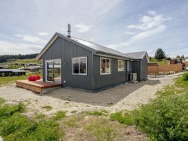 A modern house with a deck and windows at Skiwi - Wanaka Holiday Home in Wanaka