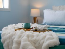 A bedroom with a bed and a tray of food on it at Skiwi - Wanaka Holiday Home in Wanaka