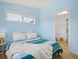 A bedroom with a bed and ensuite bathroom at Skiwi - Wanaka Holiday Home in Wanaka