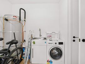 A laundry room with a washing machine and utility sink at Skiwi - Wanaka Holiday Home in Wanaka