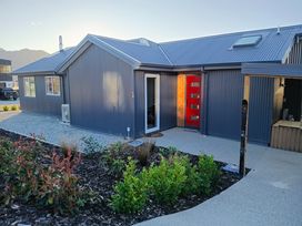 A house with a red front door and garden at Skiwi - Wanaka Holiday Home Wanaka
