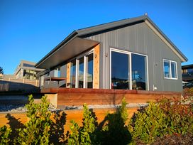 A house with large windows and a wooden deck at Skiwi - Wanaka Holiday Home in Wanaka