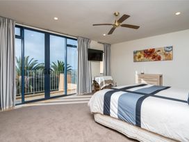 A bedroom with a bed and balcony access at Ruakaka in Ruakaka