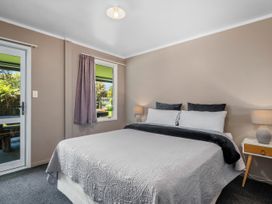 A bedroom with a bed and windows at Lakepath Retreat - Lake Rotoiti Holiday Home