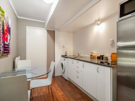A kitchen with a washing machine and glass table at Lakepath Retreat - Lake Rotoiti Holiday Home
