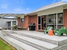 An outdoor deck with a grill and seating at Rotoiti Escape - Lake Rotoiti Holiday Home