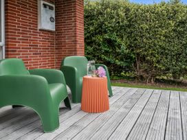An outdoor seating area with green chairs and a table at Rotoiti Escape - Lake Rotoiti