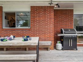 An outdoor dining area with a table and grill at Rotoiti Escape - Lake Rotoiti Holiday Home