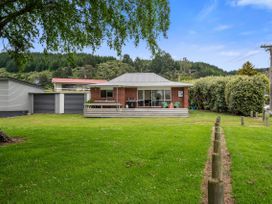 A house with a deck and grassy area at Rotoiti Escape - Lake Rotoiti Holiday Home