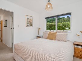 A bedroom with a bed and window at Rotoiti Escape - Lake Rotoiti Holiday Home