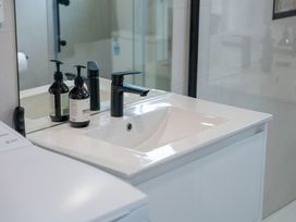 A sink with a faucet and soap dispensers in a bathroom at Lake Taupo Holiday Home in Motuoapa