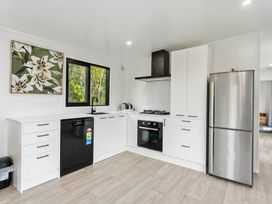 A kitchen with white cabinets, appliances, and window at Lake Taupo Holiday Home in Motuoapa