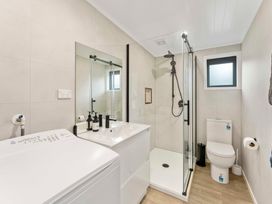 A bathroom featuring a washing machine, sink, shower, and toilet at Lake Taupo Holiday Home in Motuoapa