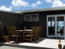 An outdoor seating area with a table and chairs at Karikari in Kaitaia