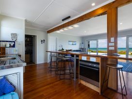 A kitchen with bar stools and an oven at Karikari in Kaitaia