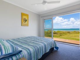 A bedroom with a bed and ocean view at Karikari in Kaitaia