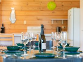 A dining room setup with glasses and a bottle at Sea Breezes - Matarangi Holiday Home, Whitianga