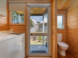 A bathroom with a washing machine and a view to the outdoor area at Sea Breezes - Matarangi Holiday Home Whitianga