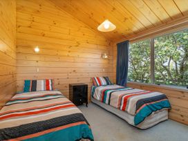 A bedroom with two beds and a nightstand at Sea Breezes - Matarangi Holiday Home in Whitianga