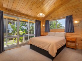 A bedroom with a bed and nightstand at Sea Breezes - Matarangi Holiday Home, Whitianga