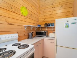 A kitchen with a stove, microwave, and refrigerator at Sea Breezes - Matarangi Holiday Home Whitianga