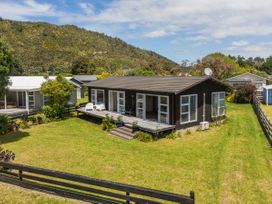 A house with a deck and garden at Matarangi Holiday Home in Whitianga