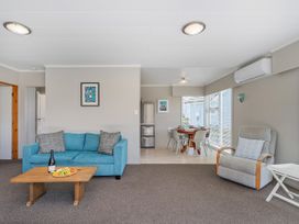 A living room with a sofa and dining area at Matarangi Holiday Home Whitianga